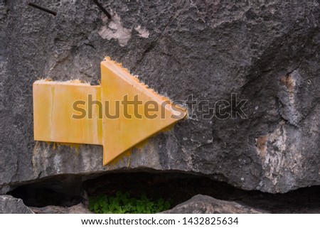 Yellow navigation symbol on the rock wall of a natural mountain, Limestone mountains,to the right