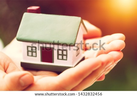 Mini home in a human hand on background