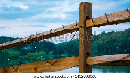 A beautiful country fence covered with string lights, with a panoramic view of a lake