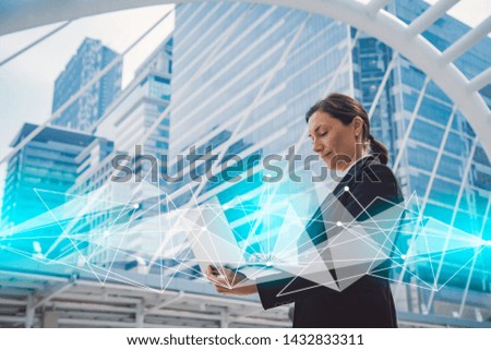 Happy young businesswoman working on laptop computer in the city.Modern city with network connection concept.global network,data exchanges,communication,smart city.
