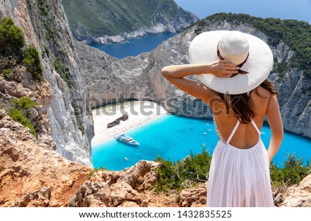 Attractive traveler woman stands on a cliff and enjoys the breathtaking view to the famous shipwreck beach, Navagio, on Zakynthos island, Greece Royalty-Free Stock Photo #1432835525