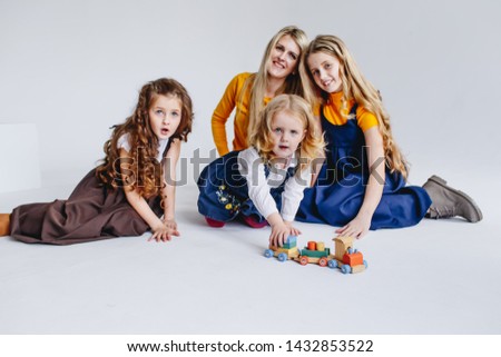 A mother with three cute daughters playing with wooden toy train. A family of four girls. A concept of big family