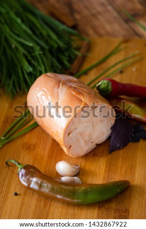 Smoked white meat with fresh vegetables on a wooden background. Photo from above