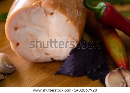 Smoked chicken closeup photo. Meat surrounded by vegetables on a wooden background