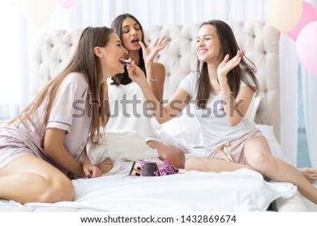 Pajama party. Attractive young smiling women in pajamas drinking champagne while having a slumber party in the bedroom