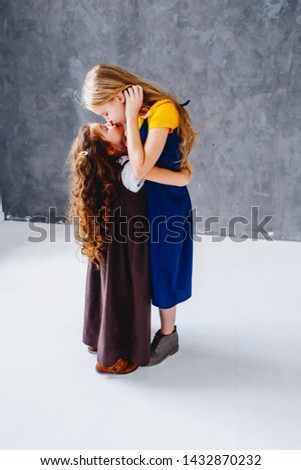 Two sisters having fun and kissing. Togertherness and friendship. Girls in long old fashioned dresses