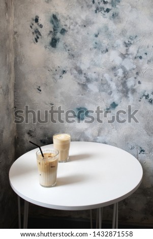 Two tall glasses of latte coffee on white table in cafe.