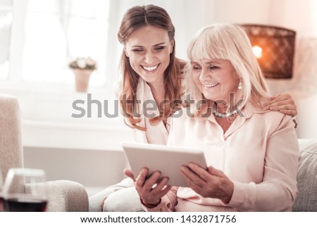 We are happy. Amazing mother and daughter smiling tenderly to each other while sitting on the sofa