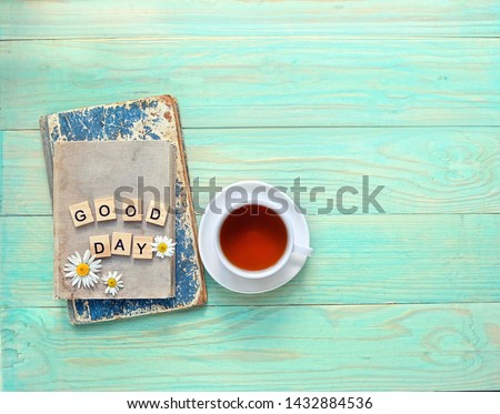 Good day. chamomile flowers, tea Cup, old books on wooden table background. tea ceremony, breakfast. flat lay. copy space