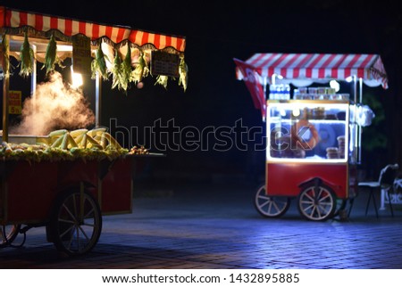 Street food carts in night with text on signboards in translation from Turkish language on English is Roasted chestnuts and corn. Royalty-Free Stock Photo #1432895885