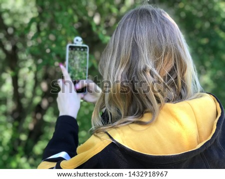 Beautiful and young girl on the phone takes pictures of nature.