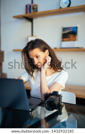 Freelance photographer woman with camera at home editing photos on computer