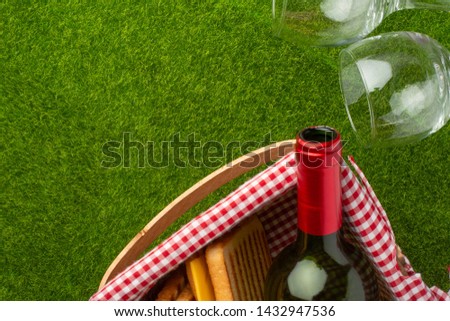 Picnic on green grass with a bottle of wine and two glasses with a picnic basket in which the senviches and fruits. background of rest and relaxation. Summer relaxation and mood.