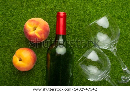Picnic on green grass with a bottle of wine and two glasses and peaches. background of rest and relaxation. Summer relaxation and mood.