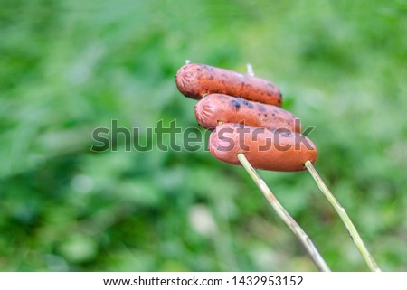 Grilling sausages over an open fire outdoors
