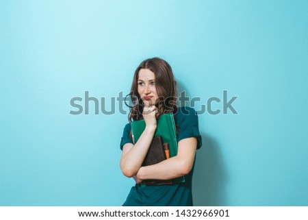 Image of a beautiful girl holding a map and school books over blue background