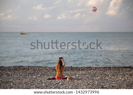 Batumi, Georgia - Girl in red bikini takes pictures of parasailing
