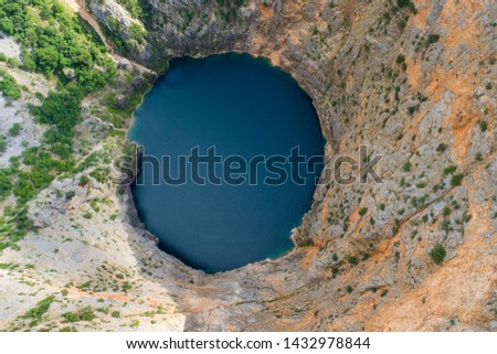 Beautiful nature and landscape photo of Red Lake in Imotski Dalmatia Croatia on warm summer day. Nice colorful image of mountains and lake shot with drone from above.