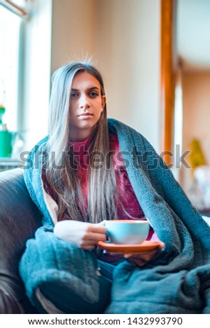 Beautiful blonde woman holding cup of tea or coffee. Looking tv and drink tea. Good morning with tea.