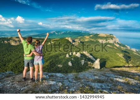 Two happy hikers with raised hands in a rocky mountains of Crimea. Travel concept.