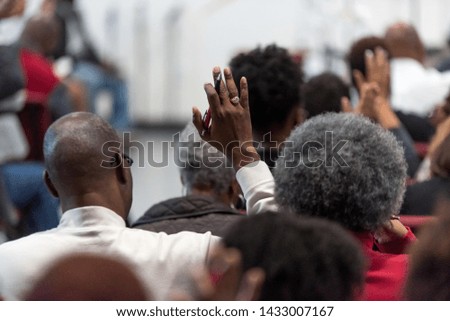 African American Man in a White Suit at Church with His Hand Raised