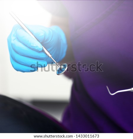 In the office of the dental clinic. The doctor holds tools for examination of teeth in blue sterile gloves.
