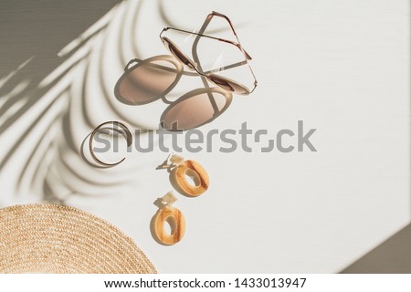 Fashion composition with women's accessories on white background with floral shadow. Earrings, sunglasses, bracelet, straw hat on white background. Flat lay, top view french style lifestyle blog