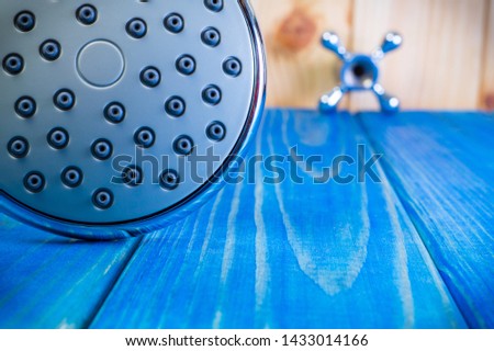 Shower head on blue wooden background and other plumbing parts close up.