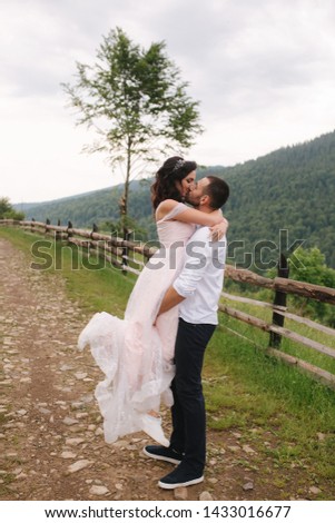 Groom kiss his beautiful bride. Couple walking in mountains
