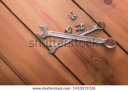 Two wrenches and some bolts are laying on a wooden surface