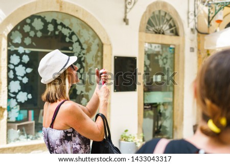 Tourist woman wearing hat making photos using smart phone on the summer holiday vacation in a sunny day