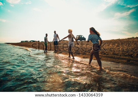 Woman and three teenagers having fun on the beach by sunset