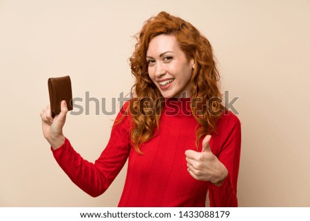 Redhead woman with turtleneck sweater holding a wallet