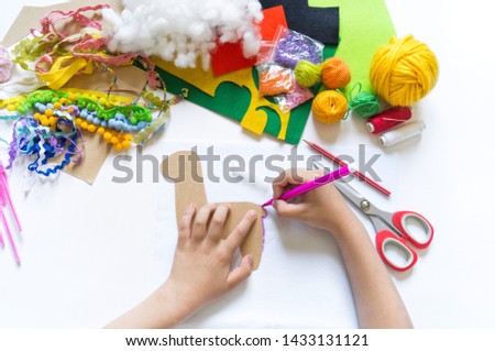 The hands of the child diy do handicraft toy lama. Felt soft craftsmanship. Material for creativity and imagination. Summer trend.