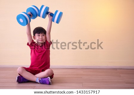Portrait Asian cute  boy. He is sitting with Dumbbell.He is action in room.Child boy raise dumbbell.lovely,nice,cute,
photo concept freedom  and  Kid portrait.