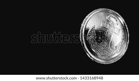 Metal button with an anchor on a black background