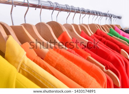 Row od colorful clothes ,long sleeve shirt and red skirt ,sweater on hanger
