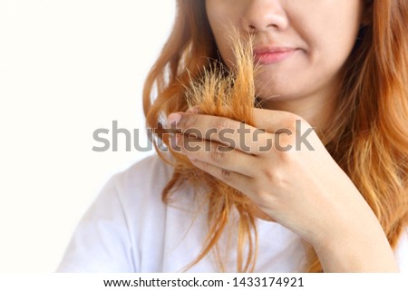 Asain woman holding her long hairs that make color treatments. The hairs maybe have problem breakage (split end) .Should care or cut end of hairs. On white background. Royalty-Free Stock Photo #1433174921