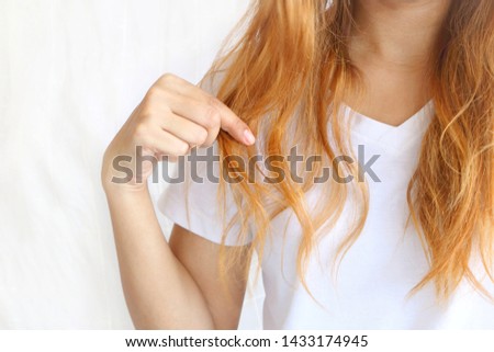 Asain woman holding her long hairs that make color treatments. The hairs maybe have problem breakage (split end) .Should care or cut end of hairs. On white background. Royalty-Free Stock Photo #1433174945