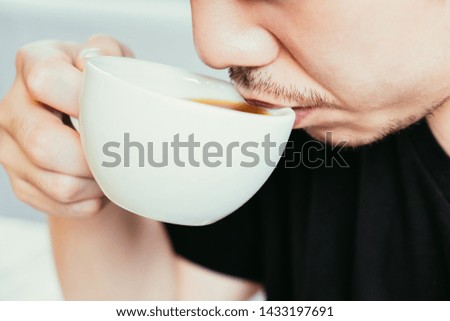 Closeup image of asian young man smelling and drinking hot coffee cup with feeling good at home.