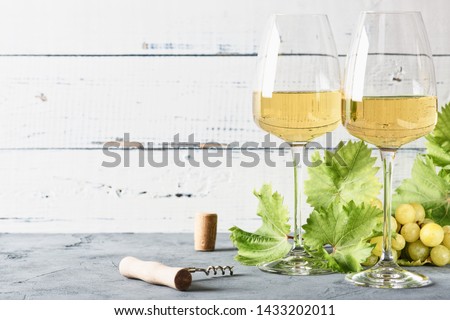 Glass of white wine on vintage wooden table. Light background