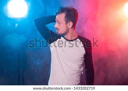 Slim young bearded hipster man in casual clothes posing on a red blue background. Concept of style and confidence.