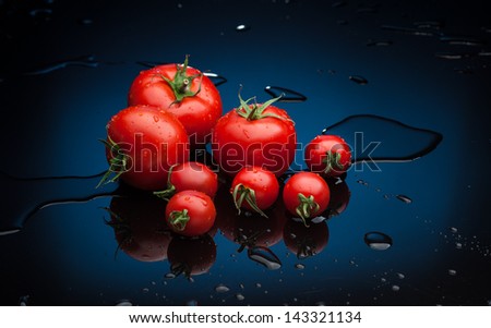 small group of fresh tomatoes lying over water splashes