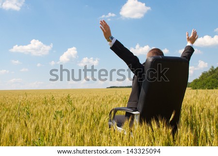 businessman in a suit sitting on a chair in a field