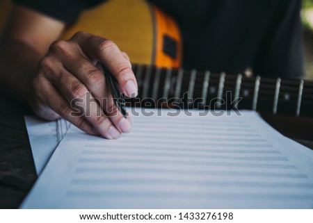 artist songwriter thinking writing notes,lyrics in book at studio.man playing live acoustic guitar relax chill.concept for musician creative.composer work process.people relaxing time with instrument. Royalty-Free Stock Photo #1433276198