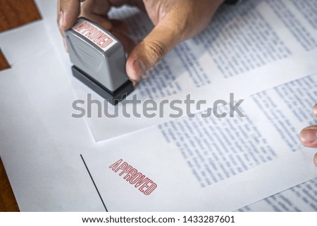 Hands of businessman stamp on paper document to approve business investment contract agreement.