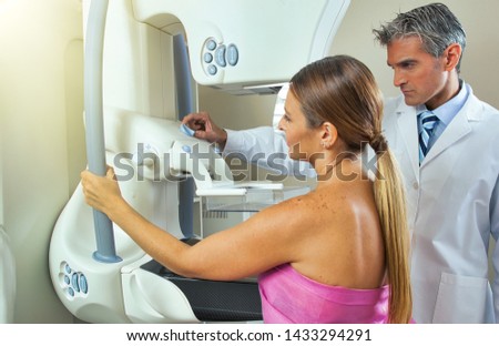 Woman undergoing breast xray under doctor supervision.