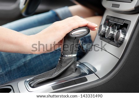 hand on automatic gear shift, woman in luxury car Royalty-Free Stock Photo #143331490