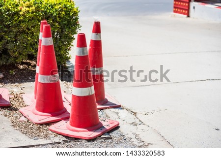 Red traffic cone on road in garden. Orange funnel use for beware car on the road in park