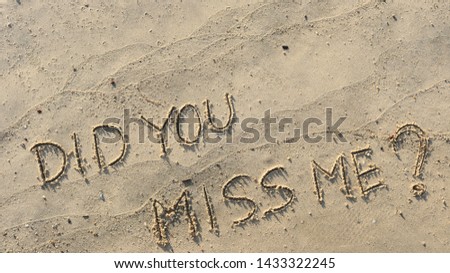Handwriting  words "DID YOU MISS ME?" on sand of beach.
